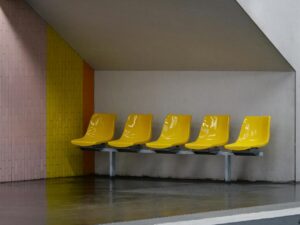 A row of bright yellow plastic chairs in a sleek, modern waiting area.