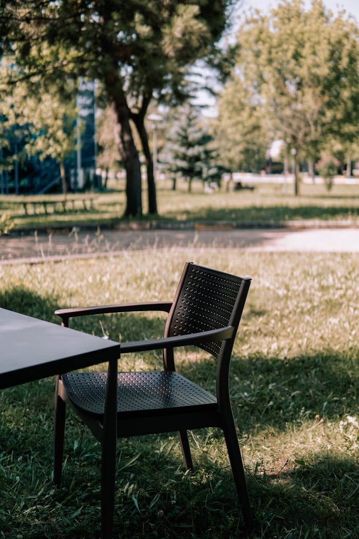 Empty Chair near Table on Grass in Park