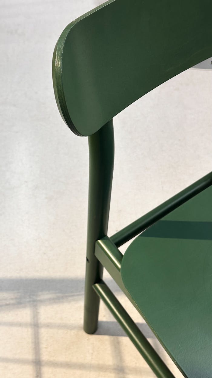 Close-up of a modern green chair with a minimalist design on a light floor.