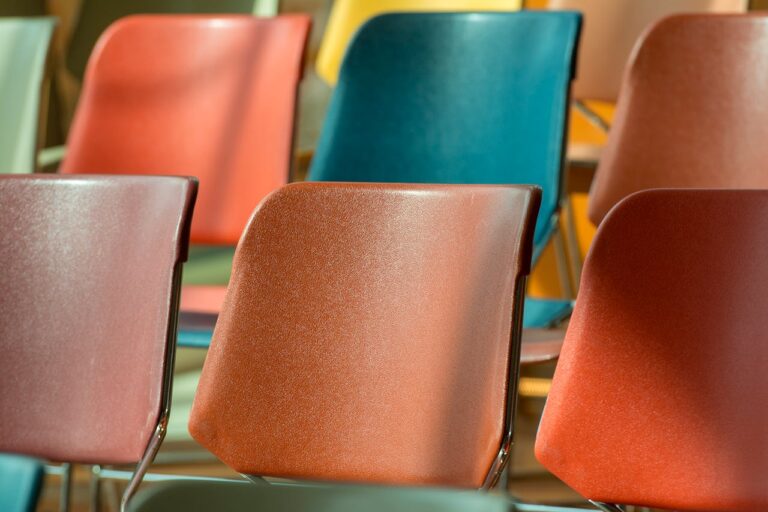 Close-up view of colorful plastic chairs arranged in soft sunlight.
