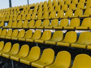 Rows of vibrant yellow plastic seats in an empty outdoor amphitheater under daylight.